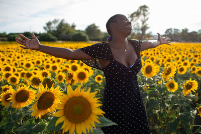 Rear view of person standing on sunflower field