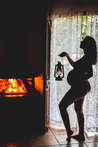 Rear view of woman standing by window