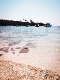 Boats moored in sea against sky on sunny day