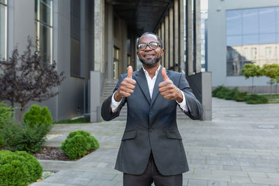 Portrait of young man standing against building