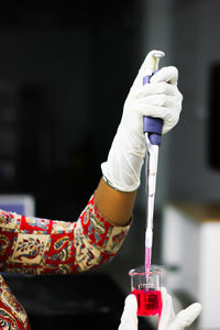 Cropped hand of scientist wearing surgical glove while working in laboratory