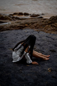 Mid adult woman sitting on rock at beach