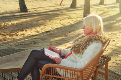 A middle-aged woman with blonde hair sits in a street cafe.