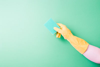 Close-up of hand holding paper against blue background