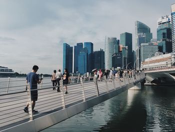 People in city at waterfront against sky