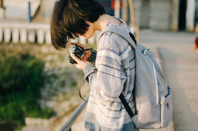 Woman photographing while standing by railing