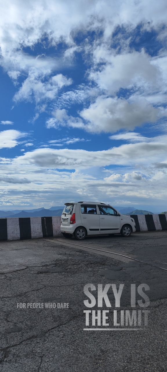 transportation, mode of transportation, motor vehicle, cloud, car, sky, vehicle, road, nature, land vehicle, sign, travel, no people, text, day, horizon, communication, land, outdoors, western script, environment, blue, parking lot