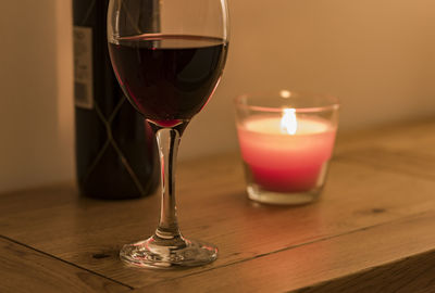 Close-up of wine and lit candle on table