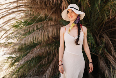 Woman wearing hat while standing against palm trees