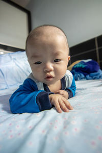 Cute baby girl lying on bed at home