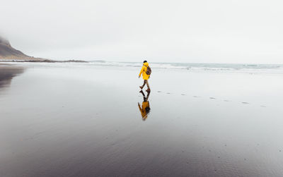 Rear view of man walking on shore at beach