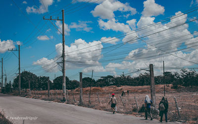 People walking on road against sky