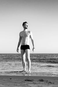 Young man standing on beach against clear sky