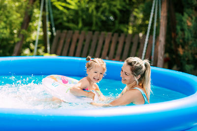 Cheerful healthy mother and daughter play in swimsuits in the pool. time together, summer time