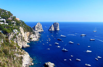 High angle view of rocks in sea against clear blue sky