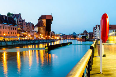 Illuminated buildings by river against sky in city at night