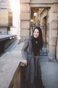 Beautiful middle-aged japanese woman in stylish coat, smiling. urban street portrait. sunlight
