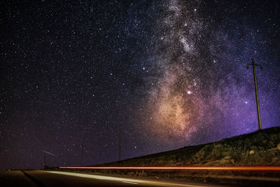 Scenic view of milky way against road at night