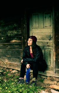 Full length of young woman sitting on wood