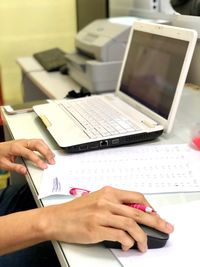 Cropped hand of businesswoman using laptop on table