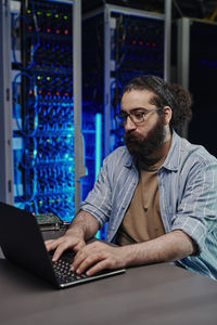 It engineer using laptop at desk in control room