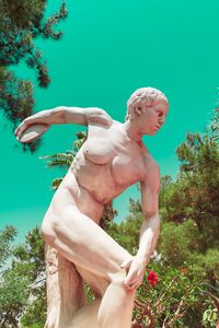 Midsection of shirtless man standing against trees