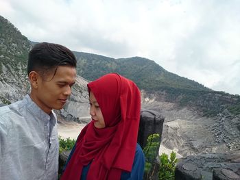 Young couple on mountain against cloudy sky