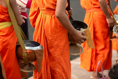 Midsection of man holding orange while standing outdoors