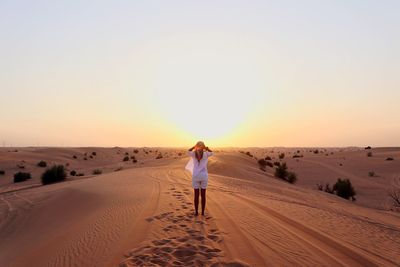 Full length portrait of man standing on sand dune in desert