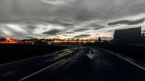 Road passing through city against cloudy sky