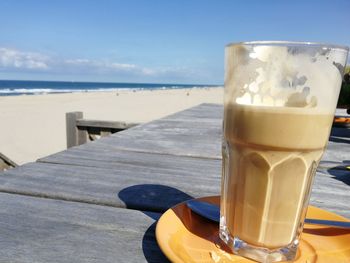 Close-up of drink on table by sea against sky