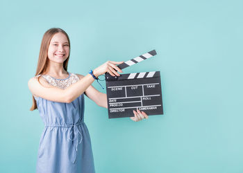 Portrait of smiling young woman standing against blue background