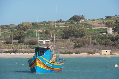 Sailboat moored on sea against clear blue sky