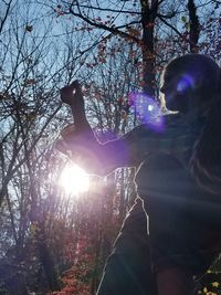 Woman standing by tree in forest