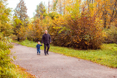 Full length of father walking on field during autumn