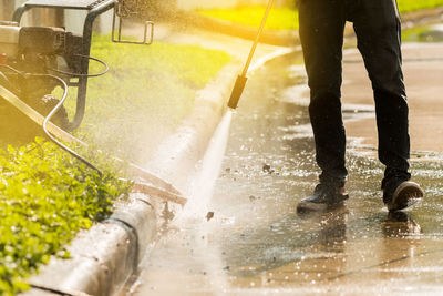 Low section of man cleaning footpath in park