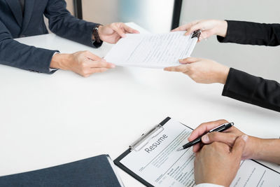 Midsection of man holding paper with text on table