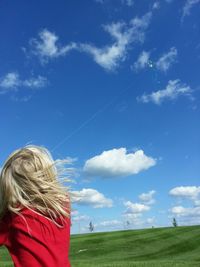 Rear view of girl flying kite against blue sky