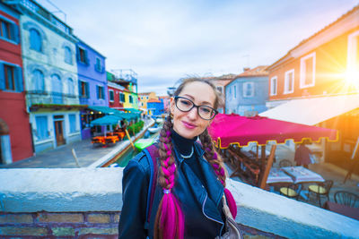 Portrait of young woman wearing sunglasses standing in city