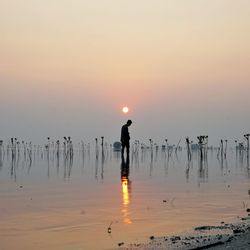 Man standing on beach against sky during sunset