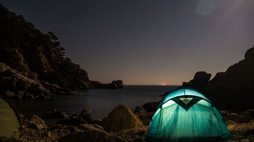 Tent on rock by sea against sky