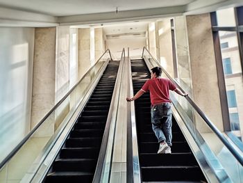 Rear view of man standing on escalator