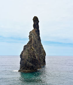 Rock formation in sea against sky