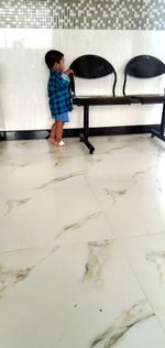 Rear view of boy standing on tiled floor