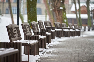 Benches covered with snow among frosty winter trees in park. winter landscape, falling snowflakes