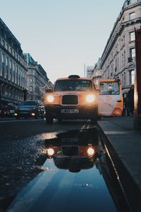 Cars on street by buildings against sky in city