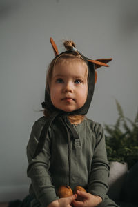 Toddler baby girl in funny dino costume sitting with eggs in hands