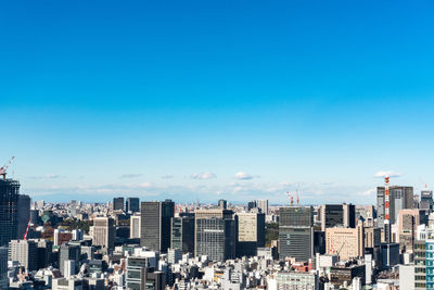 Aerial view of buildings in city against clear blue sky