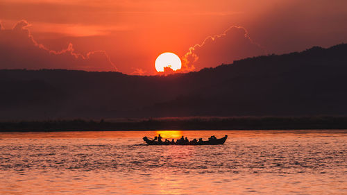 Silhouette boat in sea against sky during sunset