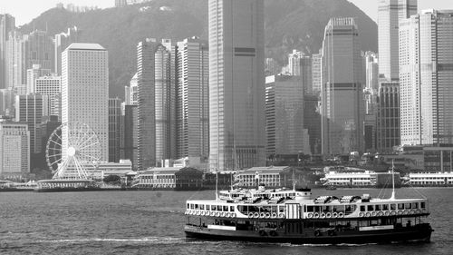 Ship in sea against modern buildings in city
